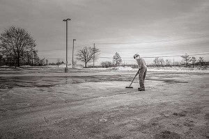 A solitary individual sweeping an empty parking lot. Courtesy of gratisography.com