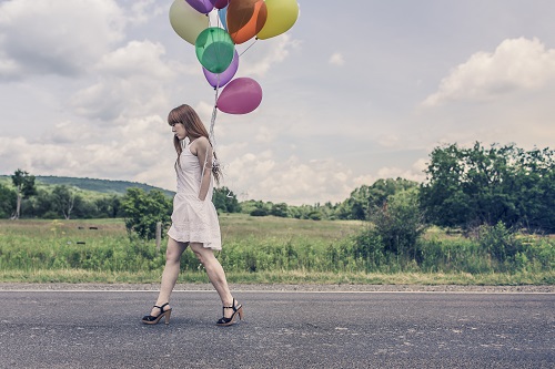 Solemn woman carrying balloons down the road; courtesy of Gratisography.com
