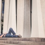A man reclines in front of large columns; courtesy of gratisography.com