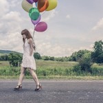 Solemn woman carrying balloons down the road; courtesy of Gratisography.com